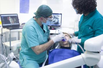 A dentist and patient, with a dental nurse standing nearby 